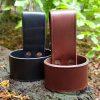two leather axe loops in black and brown on tree stump