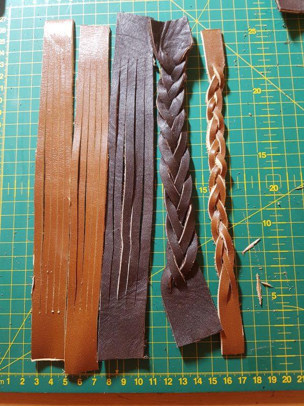 a set of mystery braid braclets in production. left to right we have to light brown cut but un braided strips of leather two in light brown and onw in dark, the na darbrown braided braclet of 5 strands in dark brown then a light brown 3 stand baclet