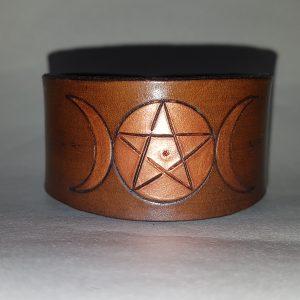 a triple moon cuff in copper dyed leathre with the goddess symbol engraved