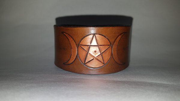 a triple moon cuff in copper dyed leathre with the goddess symbol engraved