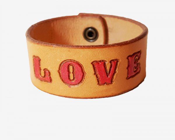 a cuff with the word love picked out in red on a natural tan background