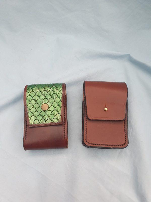 Two brown leather pouches one with green dragons skin pattern on the flap the other brown with black stitching